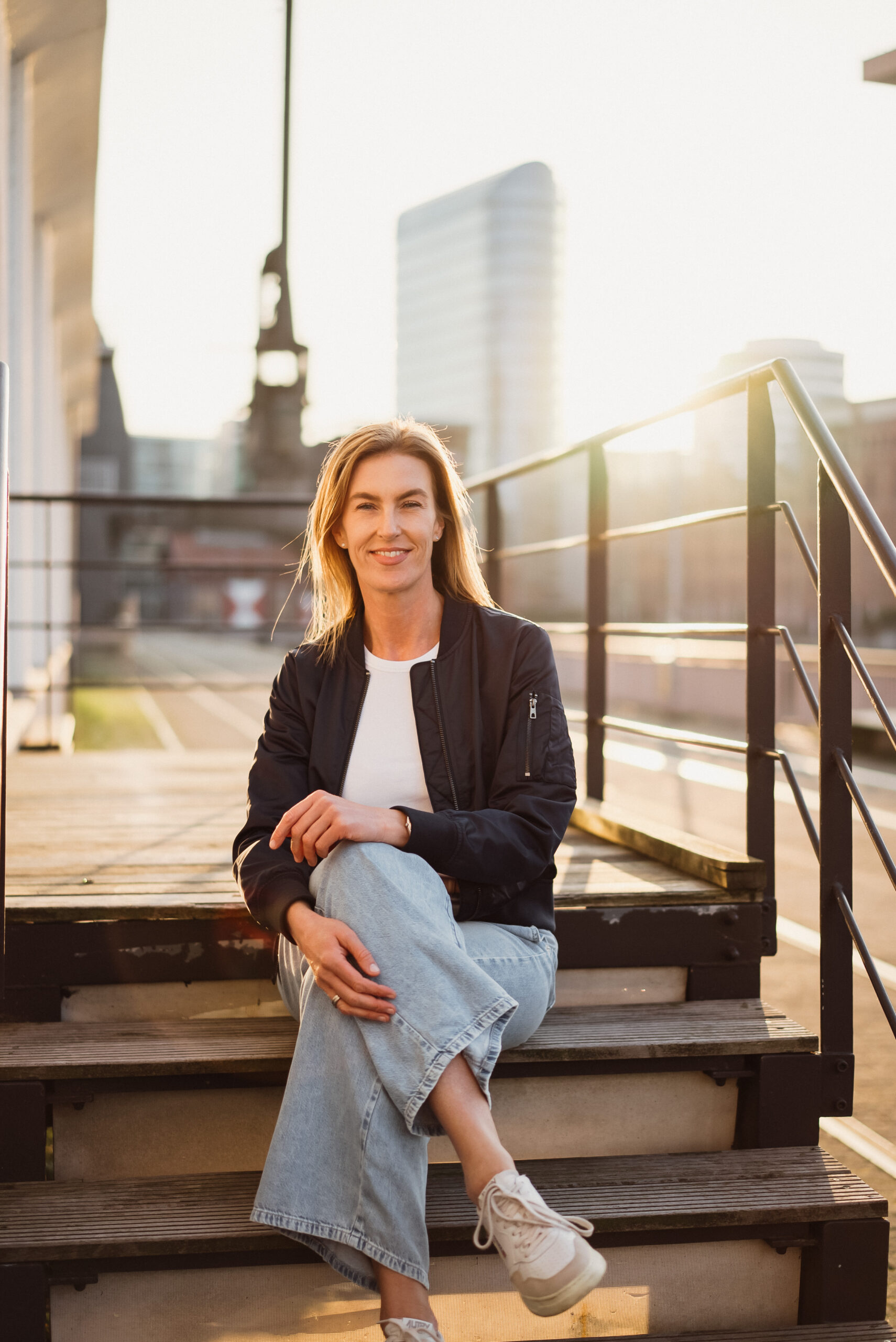 Verena Wölkhammer auf einer Treppe in urbaner Umgebung – Beraterin, Executive Coach und Organisationsentwicklerin für Veränderung und Übergänge.